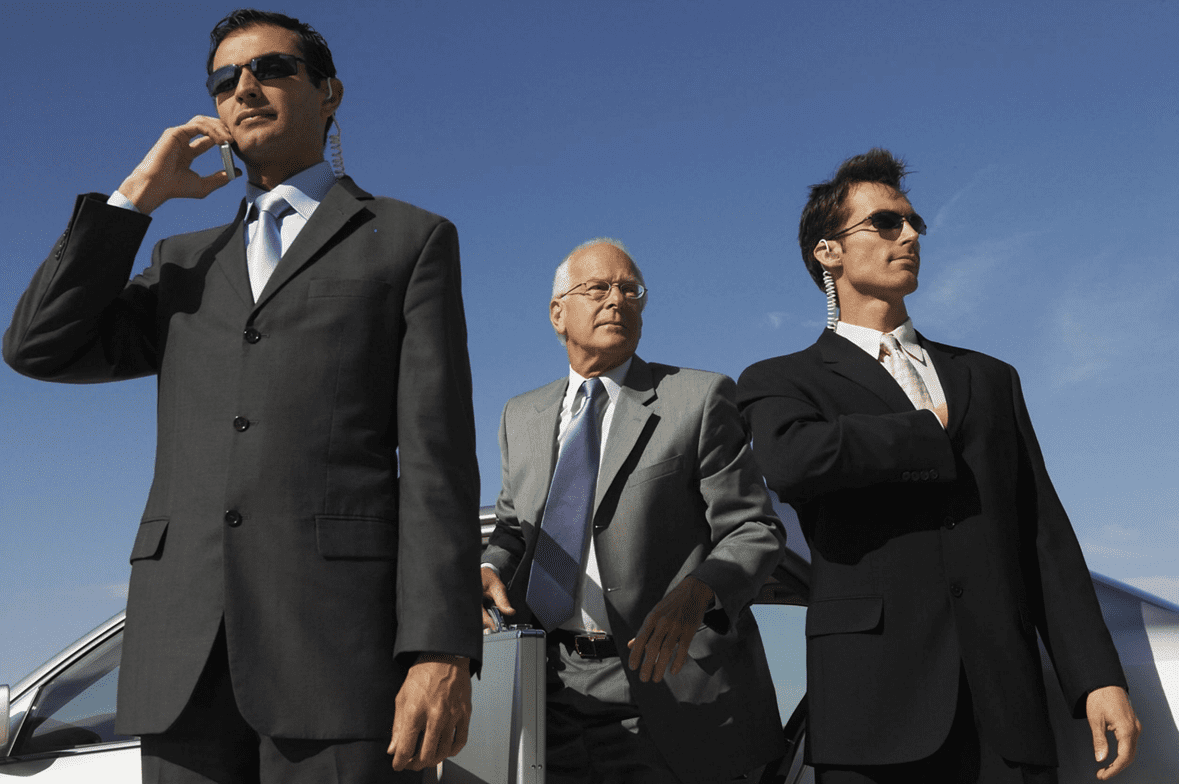 Three confident businessmen standing outdoors against a clear blue sky.