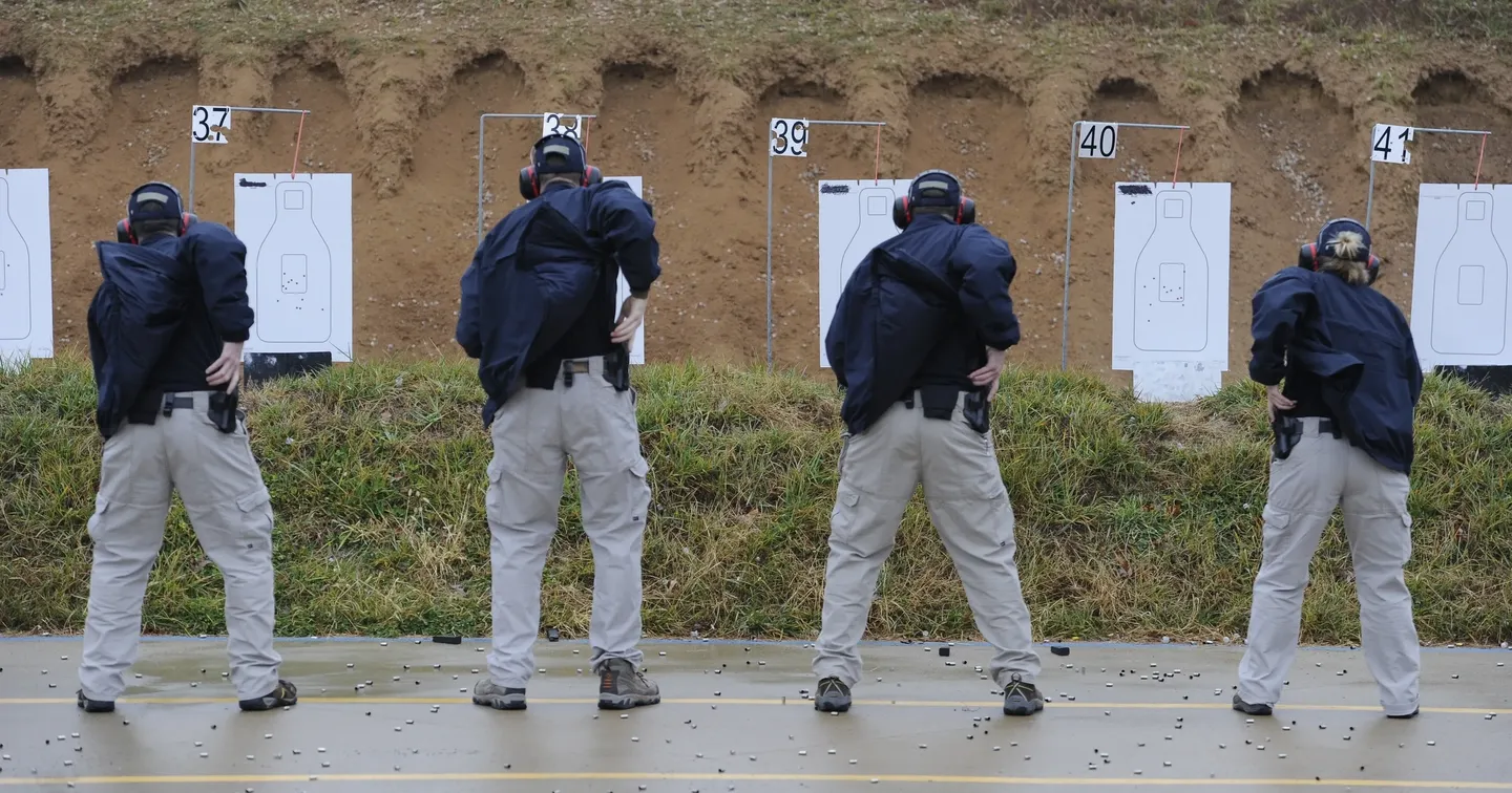 Two men practicing shooting at a target range.